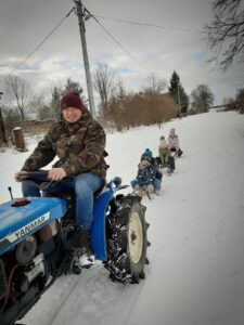Pan na traktorze ciągnący dzieci na sankach